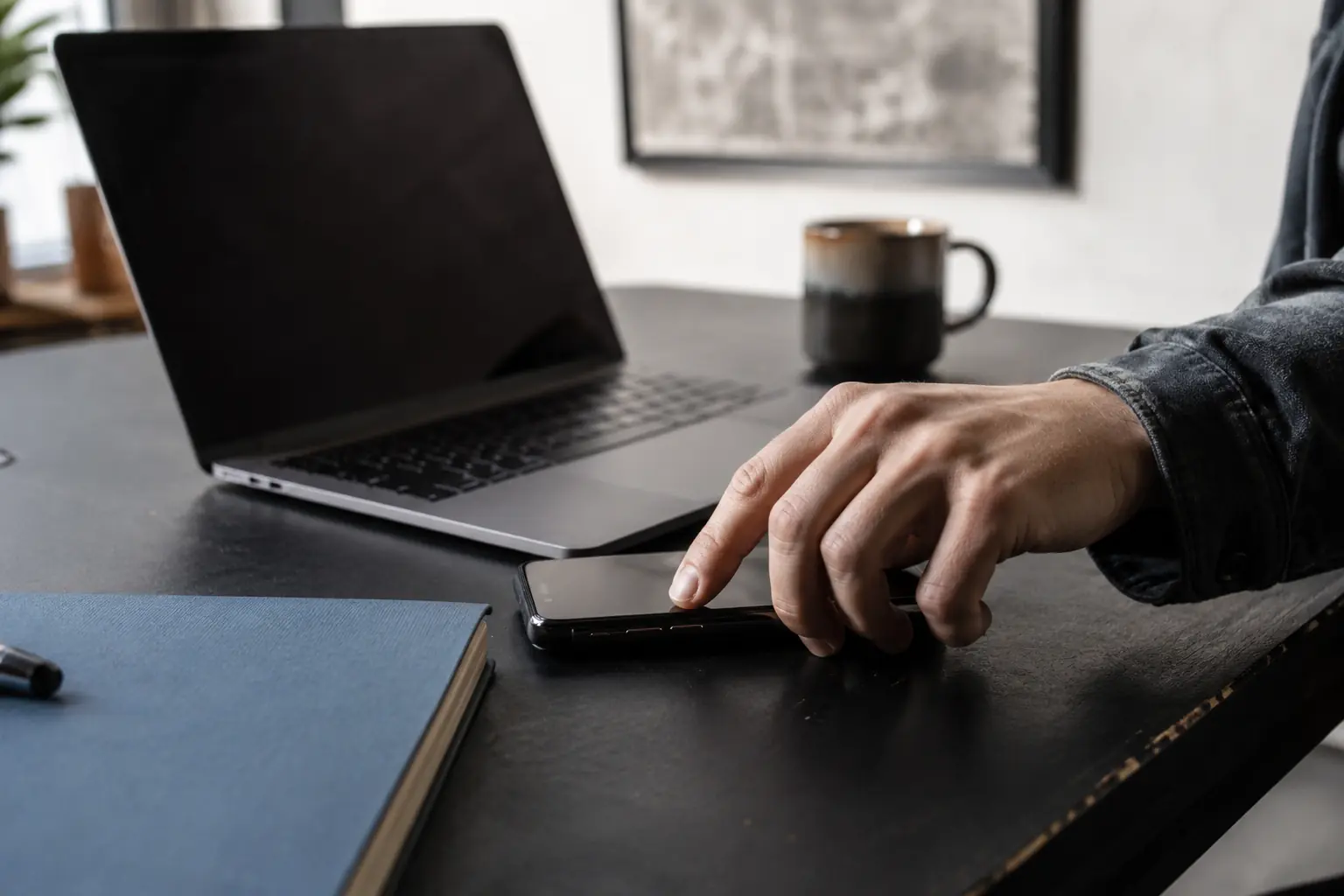 Creator securing a smartphone beside a laptop in a naturally lit workspace